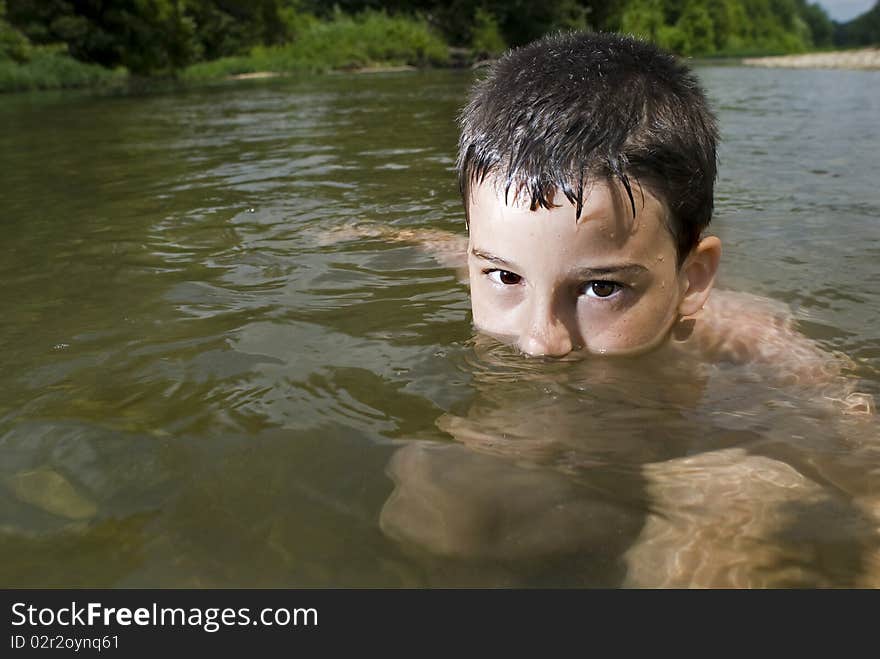 A young boy plays in a clear creek. A young boy plays in a clear creek.