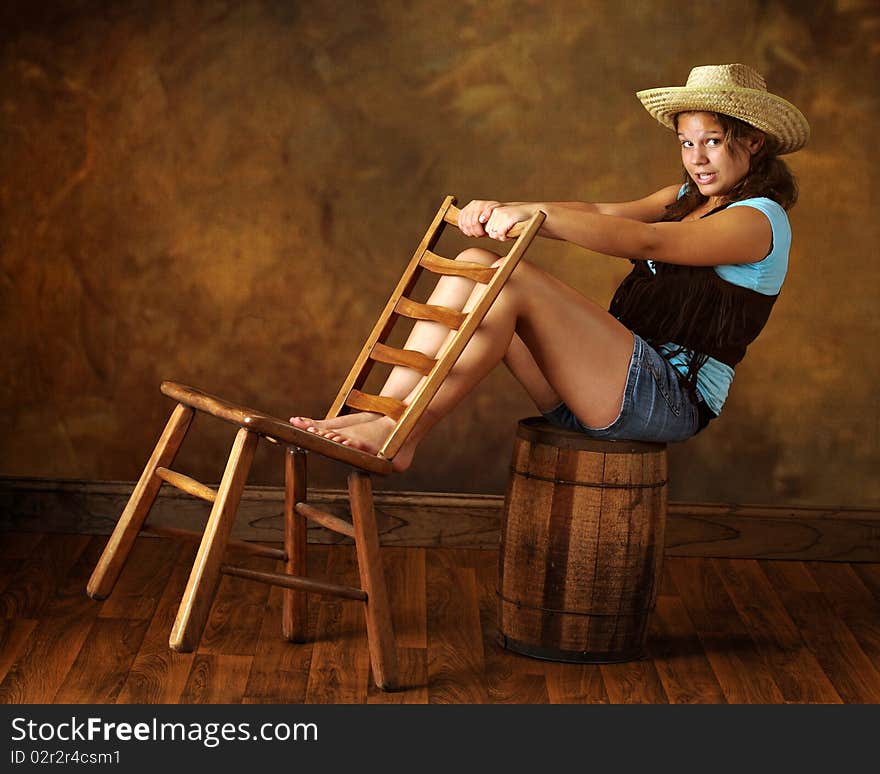 At attractive young teen leaning off an old barrel while holding on to an old wooden chair. At attractive young teen leaning off an old barrel while holding on to an old wooden chair.