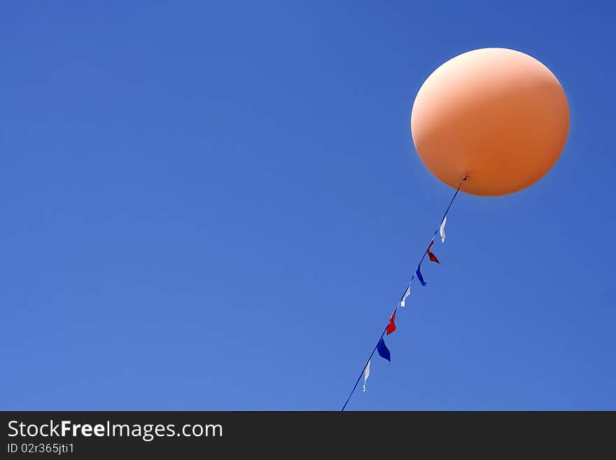 One orange balloon floating in bright blue sky. One orange balloon floating in bright blue sky