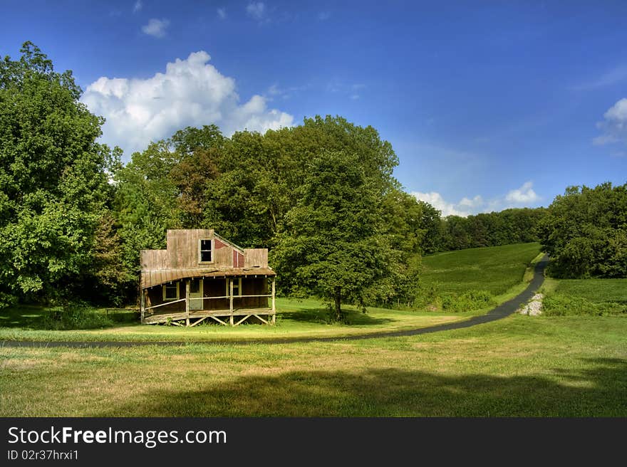 Old abandoned rustic house, green hill and trees, with blue sky and white clouds. Old abandoned rustic house, green hill and trees, with blue sky and white clouds