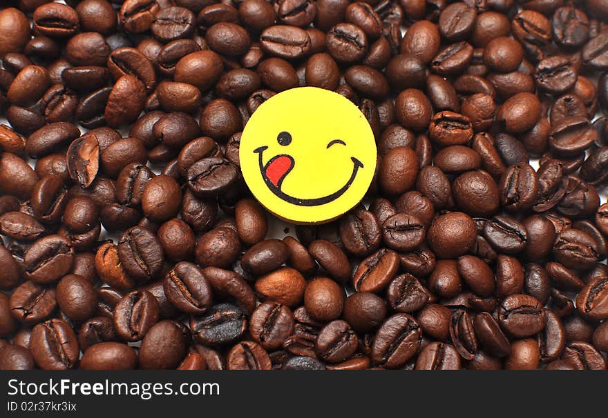 Yellow button is a happy face on the background of the coffee bean. Yellow button is a happy face on the background of the coffee bean