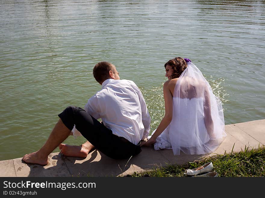 Bride and groom posing with back near water. Bride and groom posing with back near water