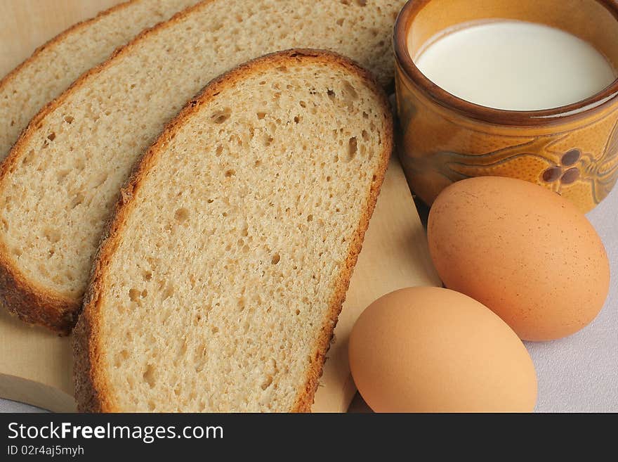 Breakfast close-up. Slices of bread, two brown eggs and cup of milk.