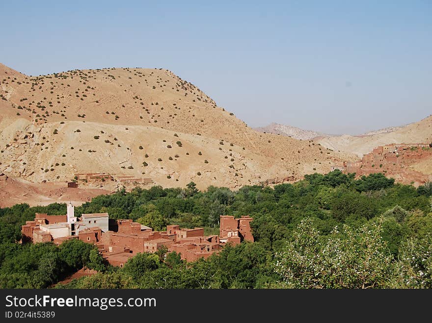 A small berber village is partially concealed by surrounding trees. A small berber village is partially concealed by surrounding trees