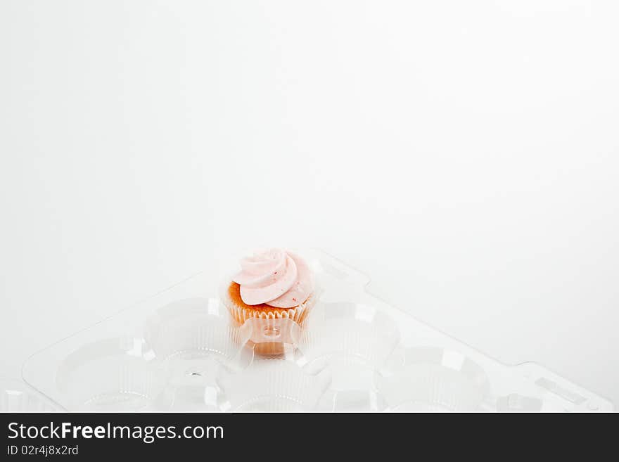 Single remaining strawberry cupcake in plastic container. Single remaining strawberry cupcake in plastic container