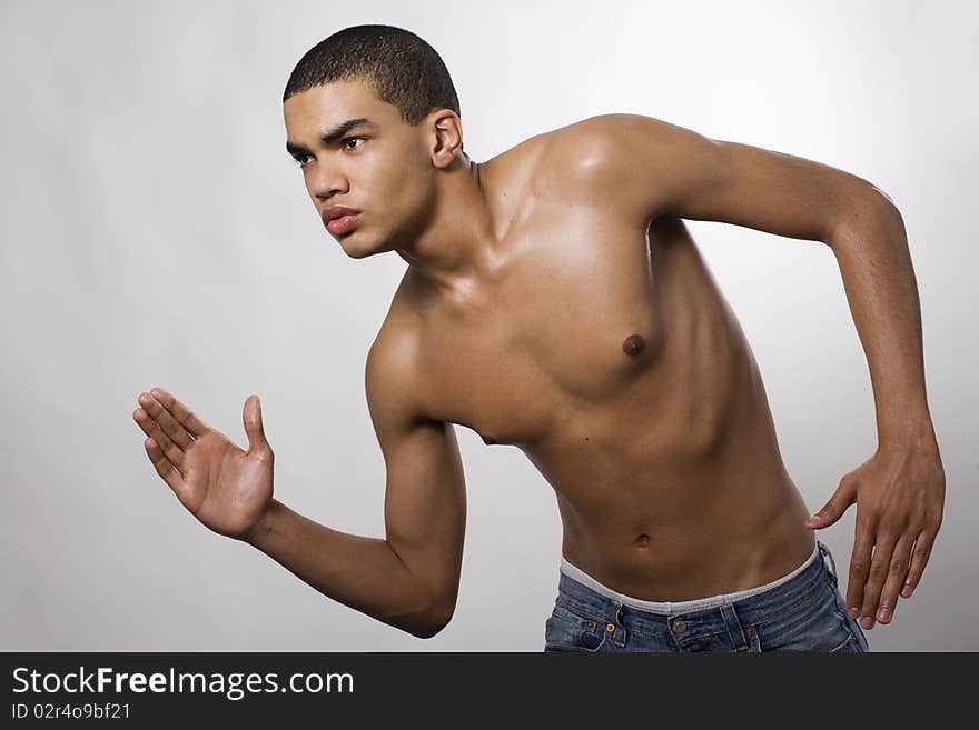 Side view of a muscular young man running in studio