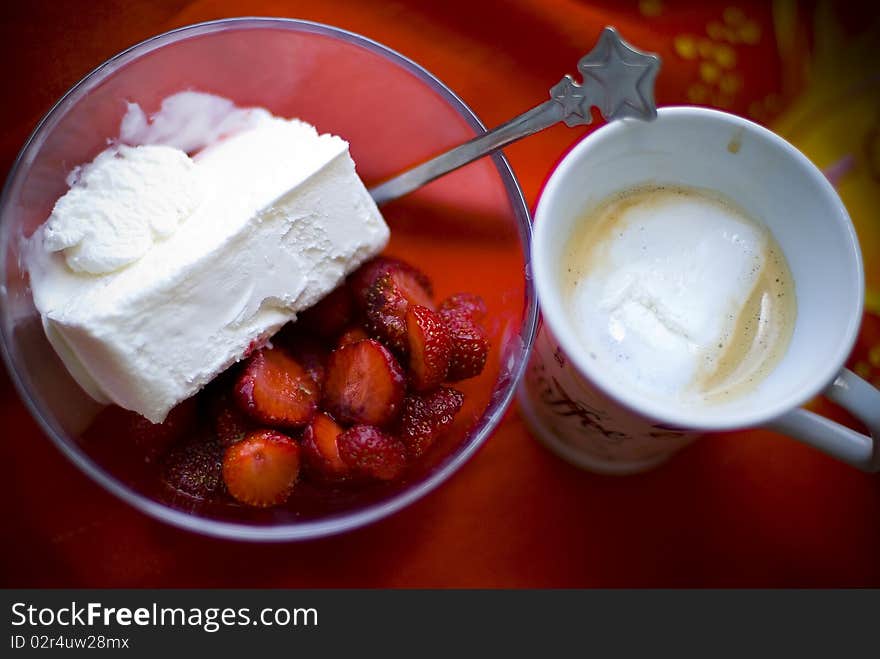 Coffee served with bowl of sliced strawberries and vanilla ice cream . Coffee served with bowl of sliced strawberries and vanilla ice cream