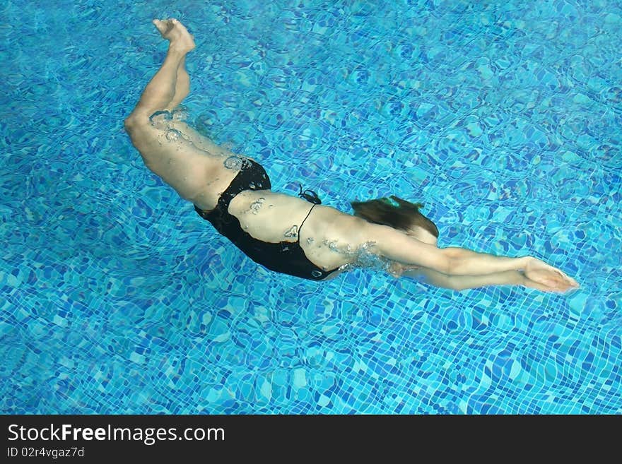 The woman floats under water in small pool