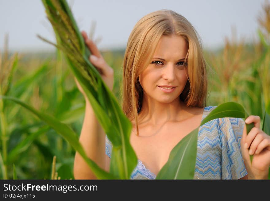 Young girl on a background of green maize and blue sky