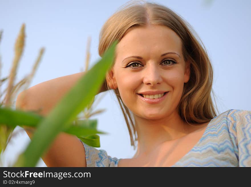 Young girl on a background of green maize and blue sky