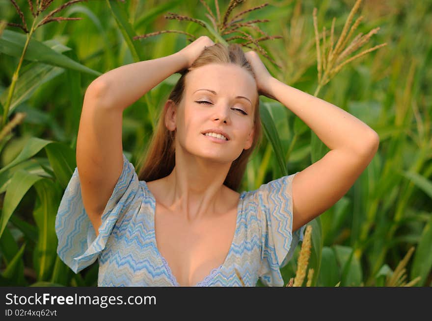 Young girl on a background of green maize and blue sky