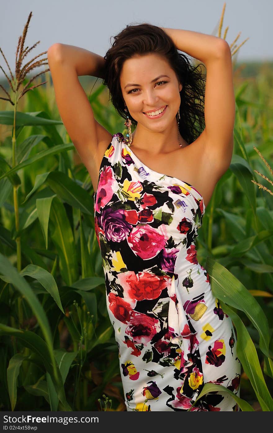 Young girl on a background of green maize and blue sky