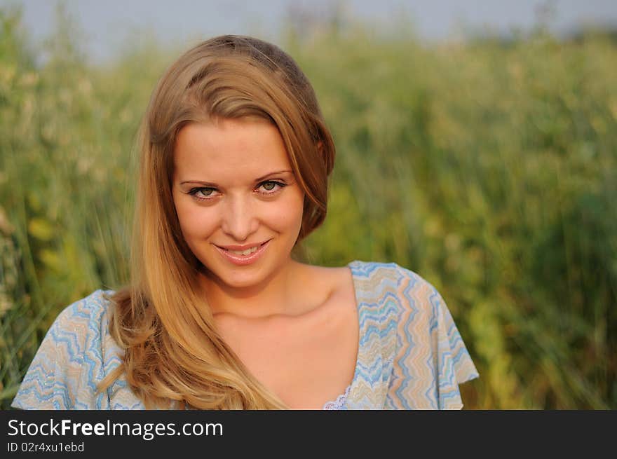 Young girl on a background of green grass and blue sky