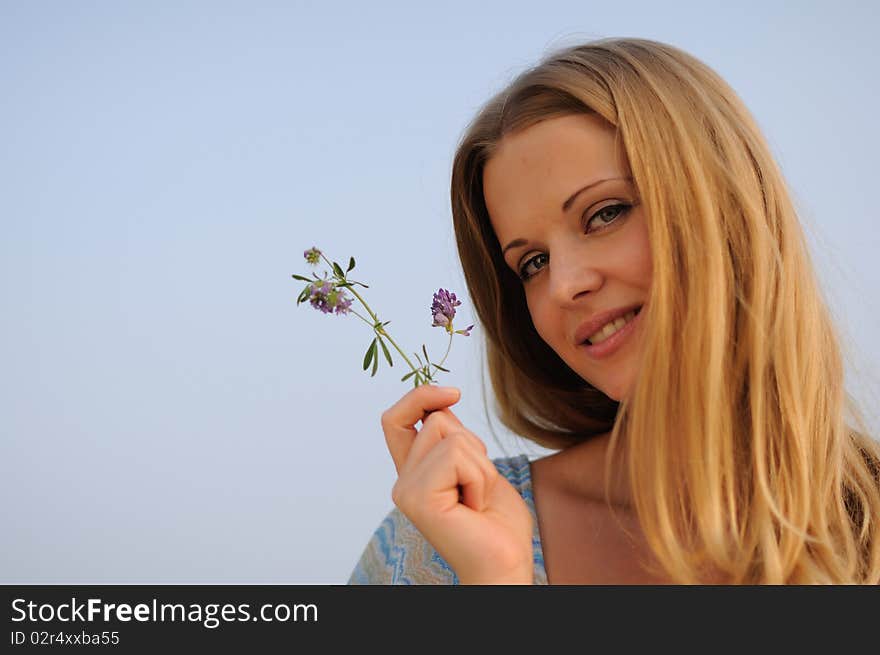 Young girl sitting on green grass against the blue sky