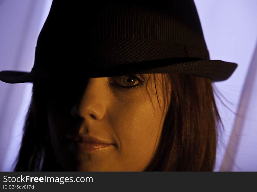 Portrait of a a beautiful young woman with red hair wearing a black pin stripe hat in mysterious strong sidelight. Portrait of a a beautiful young woman with red hair wearing a black pin stripe hat in mysterious strong sidelight