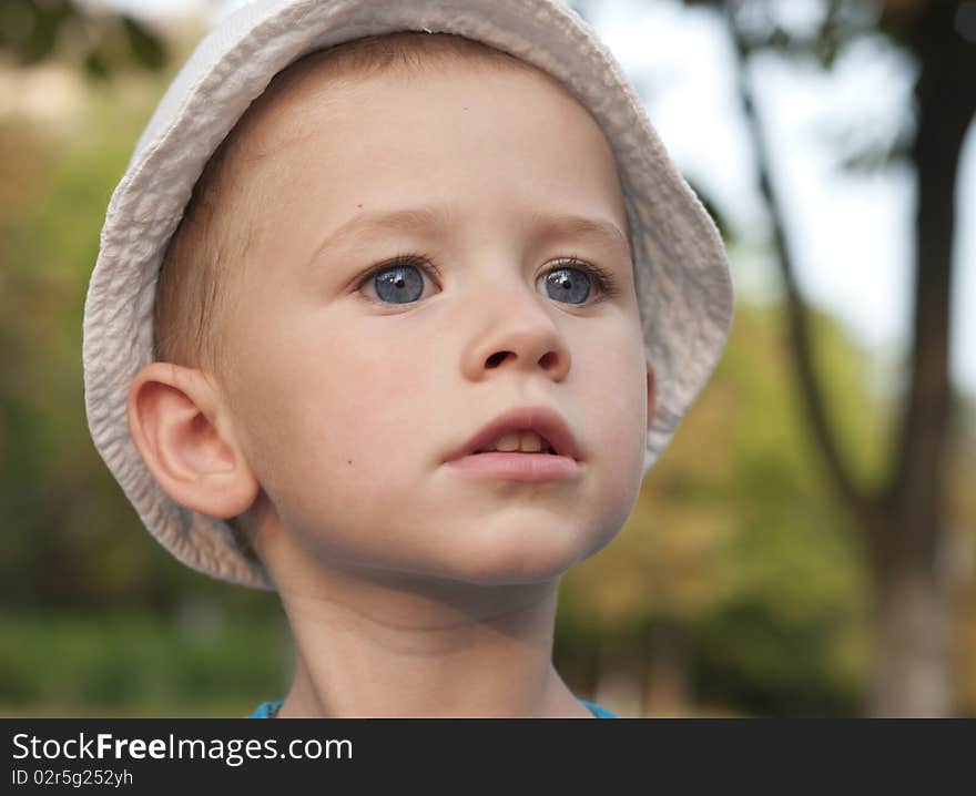 A little boy in white hat  looking forward on the street. A little boy in white hat  looking forward on the street