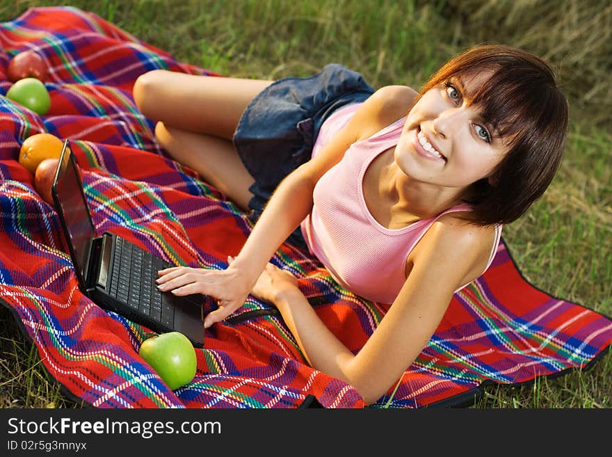 Lovely girl having a rest on picnic with laptop. Lovely girl having a rest on picnic with laptop