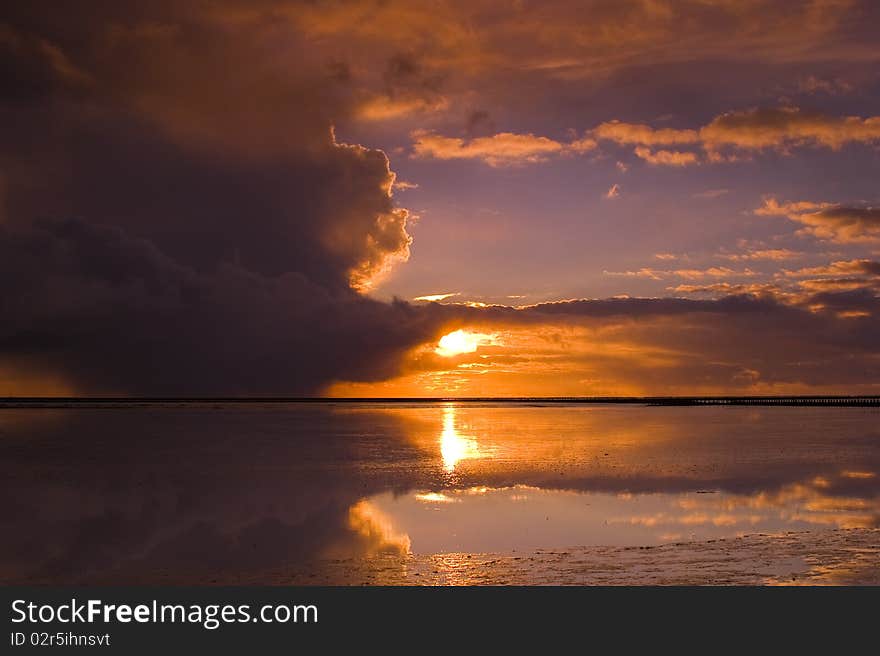 A cloudy orange sunset over the ocean. Rain is coming. A cloudy orange sunset over the ocean. Rain is coming.