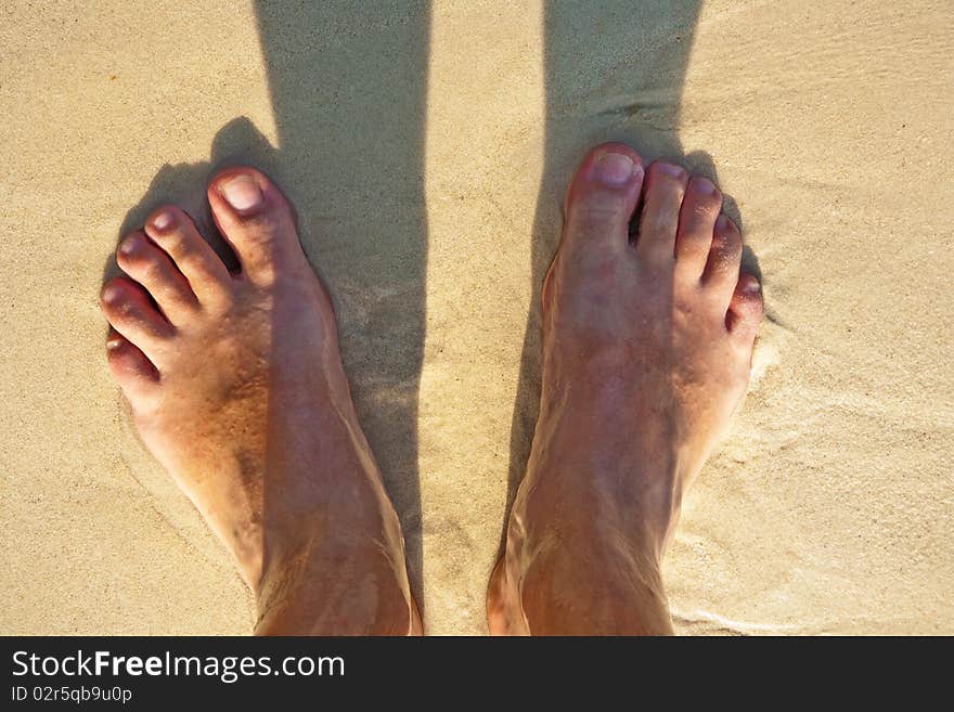 Feet of a man in the fine sand