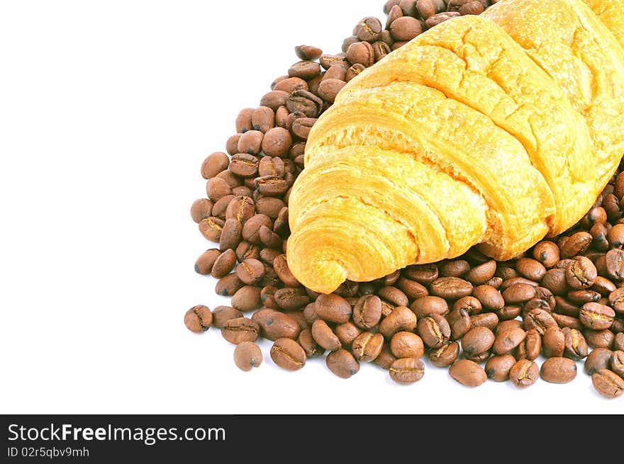 Fresh croissant over heap of coffee beans