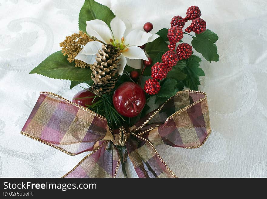 Christmas bouquet with poinsettia, berries, greenery, apples, ribbon on a brocade background