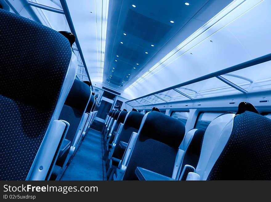 Modern railway coach interior illuminated and row of seats, monochromatic. Modern railway coach interior illuminated and row of seats, monochromatic