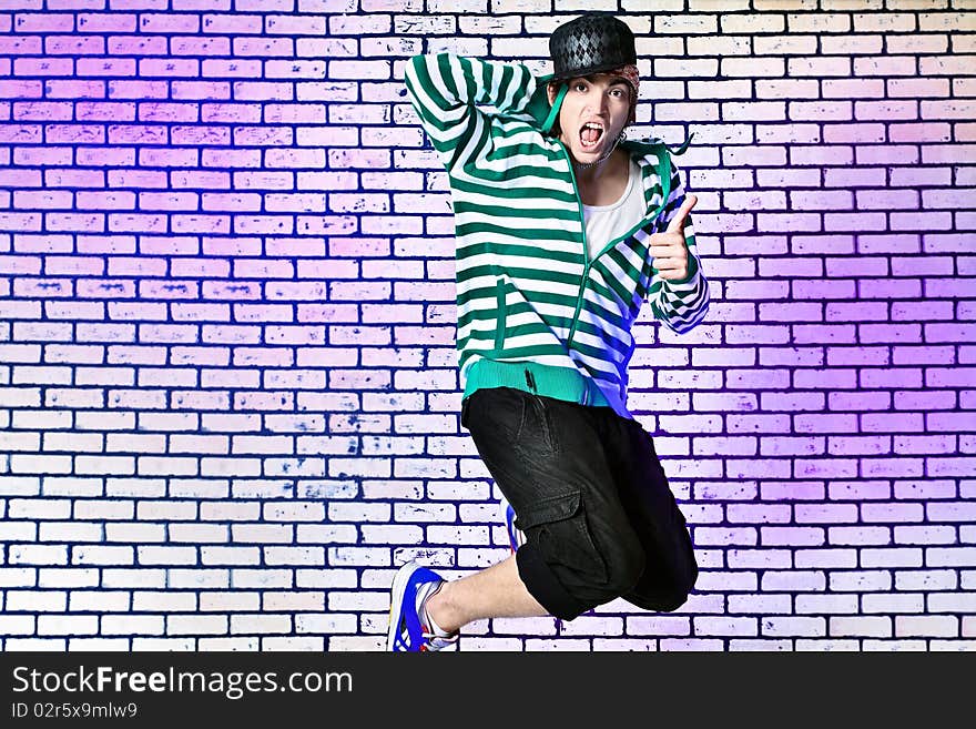 Shot of a jumping over brick background young man.