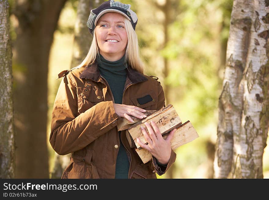 Woman Outdoors In Autumn Woodland Gathering Logs