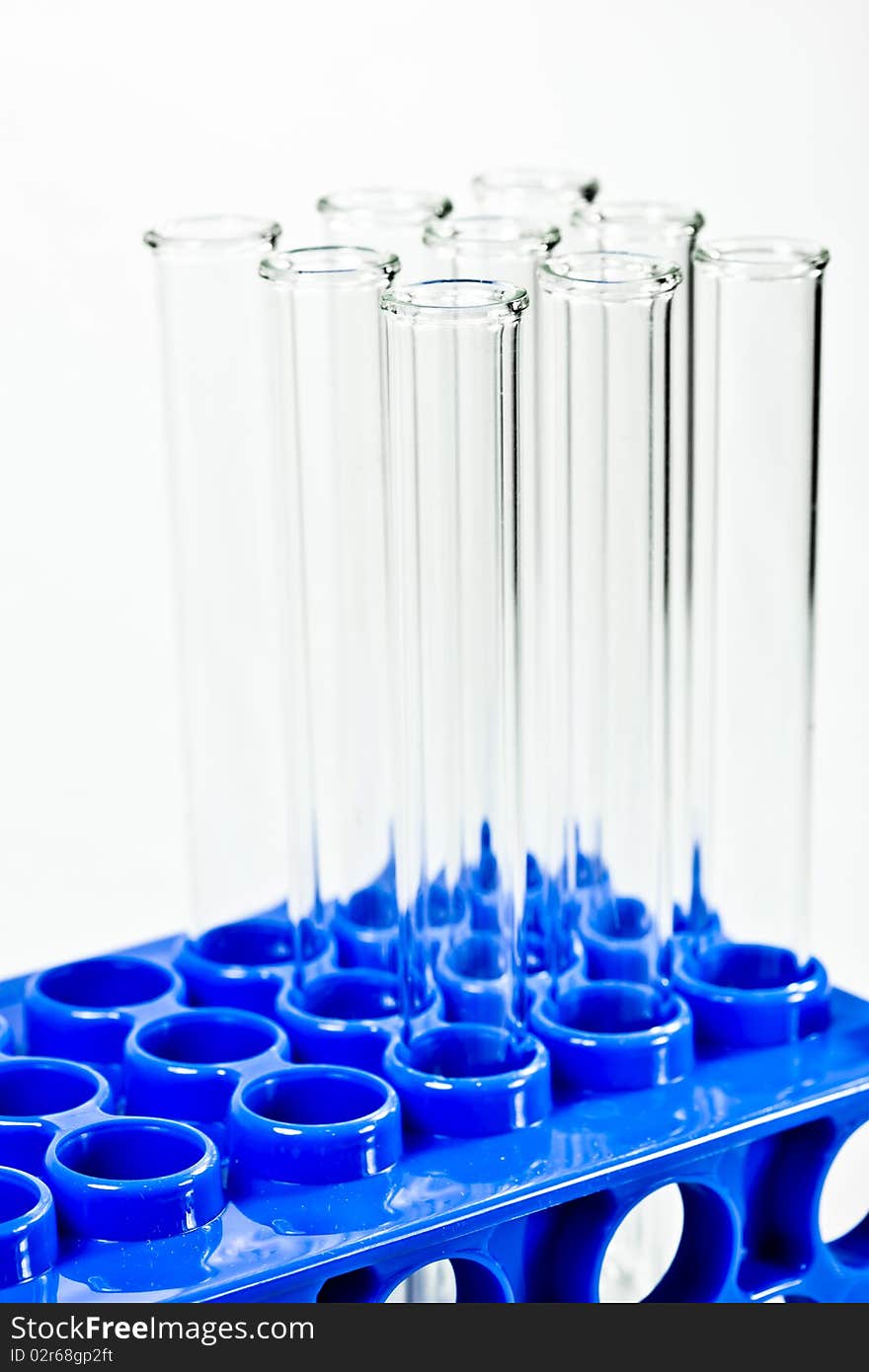 A set of empty glass test tubes in a rack with a white background. A set of empty glass test tubes in a rack with a white background