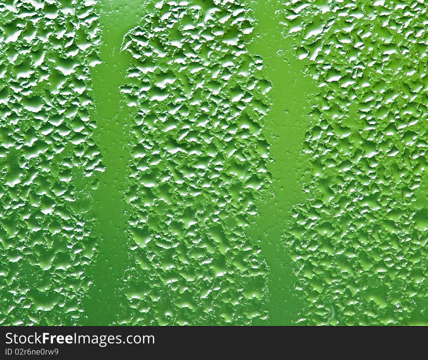 Water droplets and condensation on the window reflect the green outdoors. Water droplets and condensation on the window reflect the green outdoors