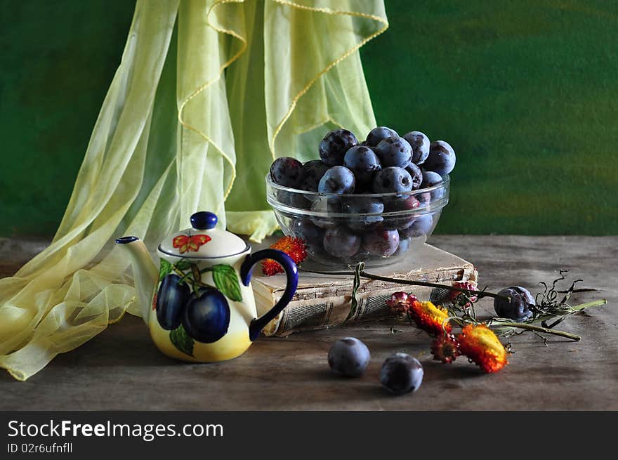 On an old table, lie, plums, tea-pot, book, dry flowers