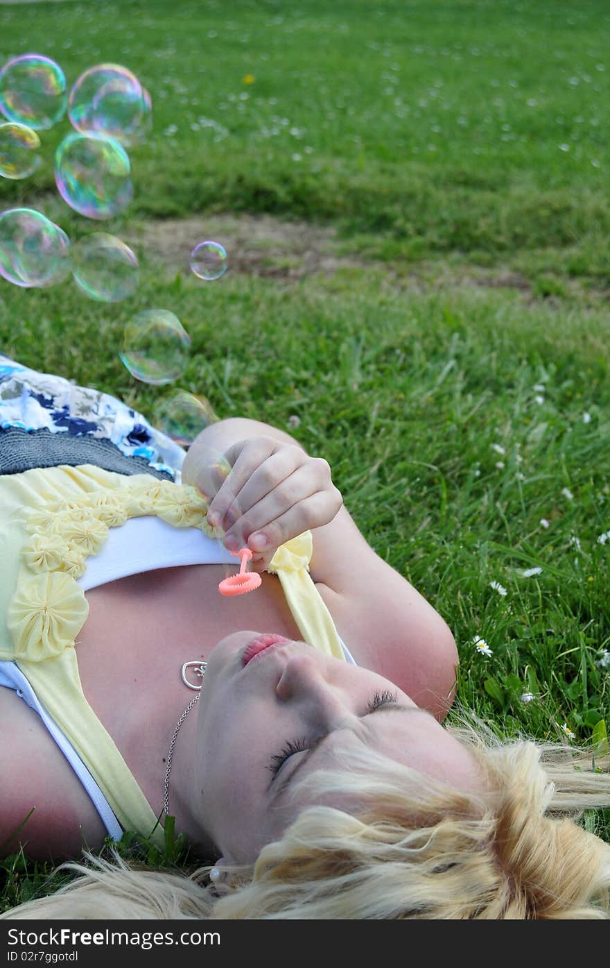 Young white Caucasian teenage girl laying in grass blowing bubbles. Young white Caucasian teenage girl laying in grass blowing bubbles.