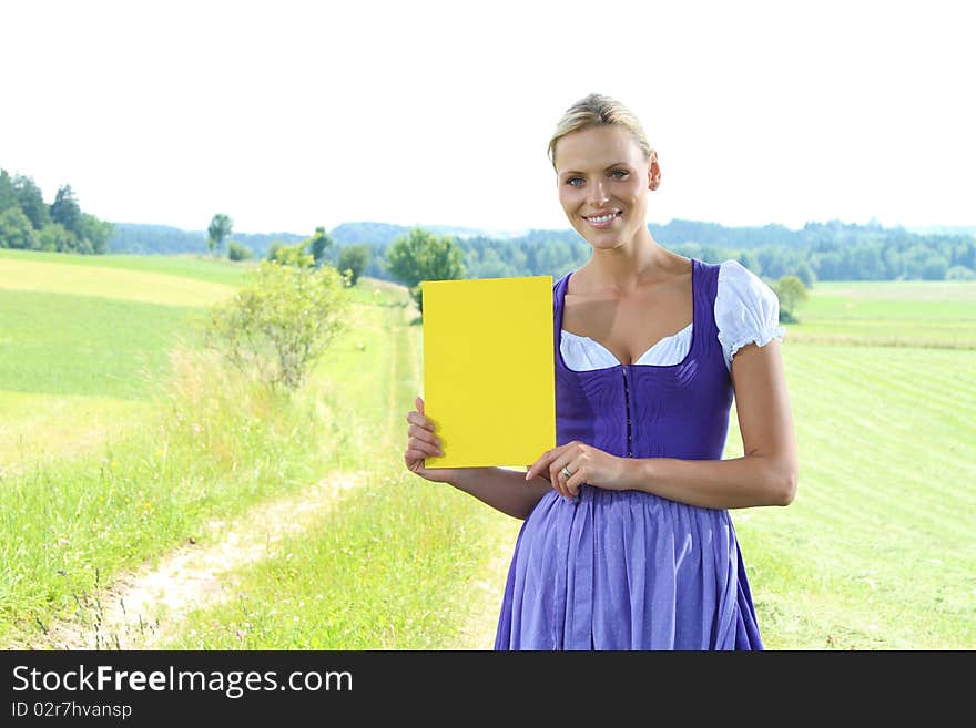 A bavarian girl standing on a meadow holding a plate