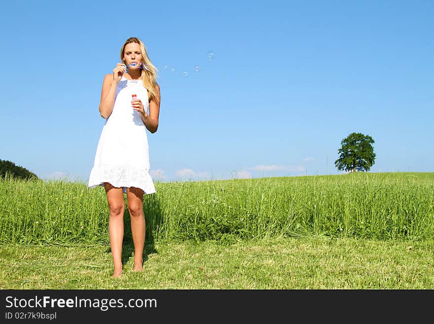 Beautiful blond Girl palying with soap bubbles