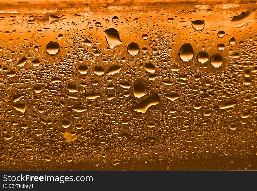 Orange condensation waterdrops on glass with a back light. Orange condensation waterdrops on glass with a back light.