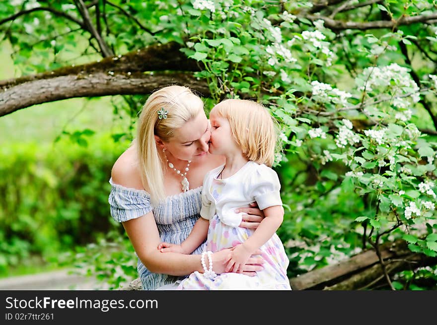 Girl kiss her mother in blooming garden