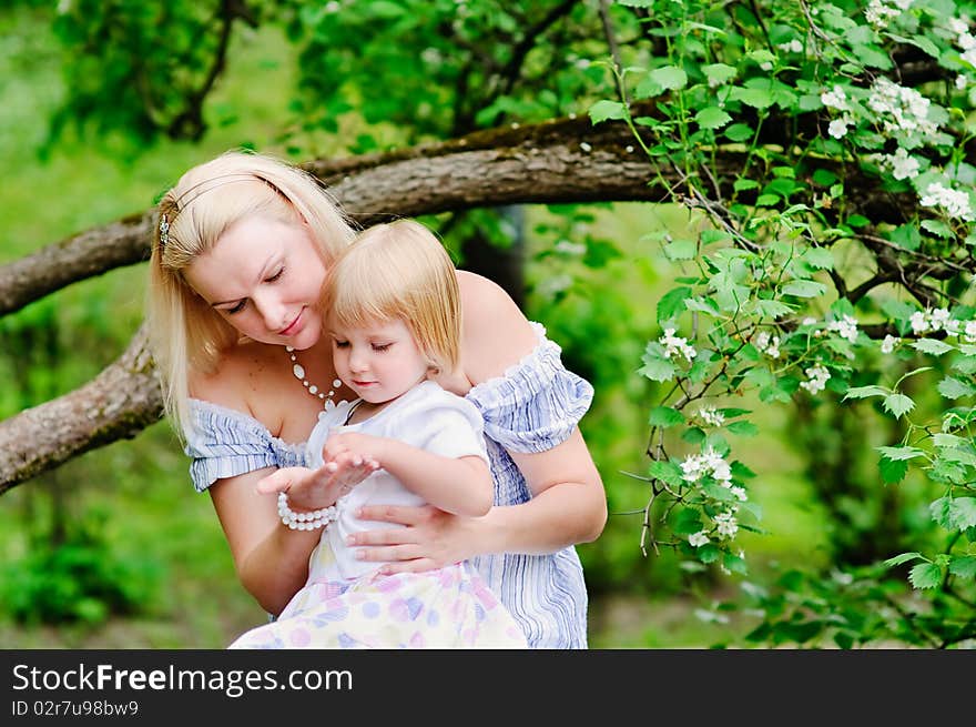 Mother And Her Daughter In Blooming Garden