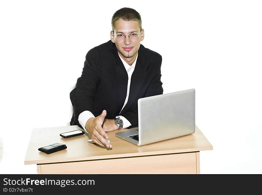 Young businessman holding hand over his desk with laptop, mouse and mobile, isolated on white background