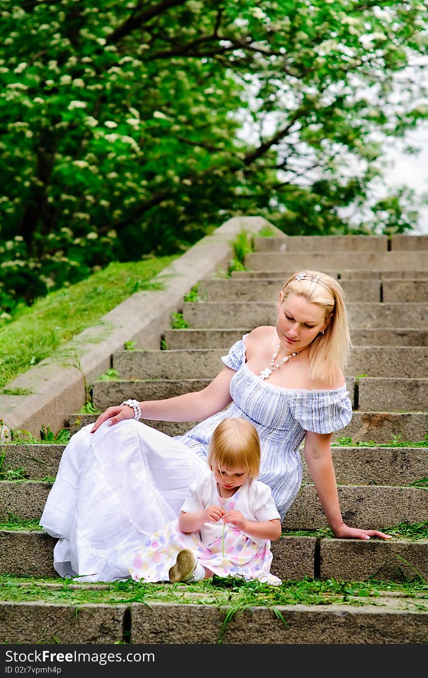 Woman And Her Baby Daughter Sit On A Stone Steps