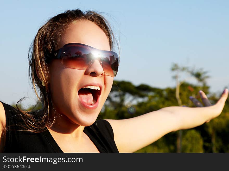 Young woman shouting with sunglasses. Sky background. outdoor image