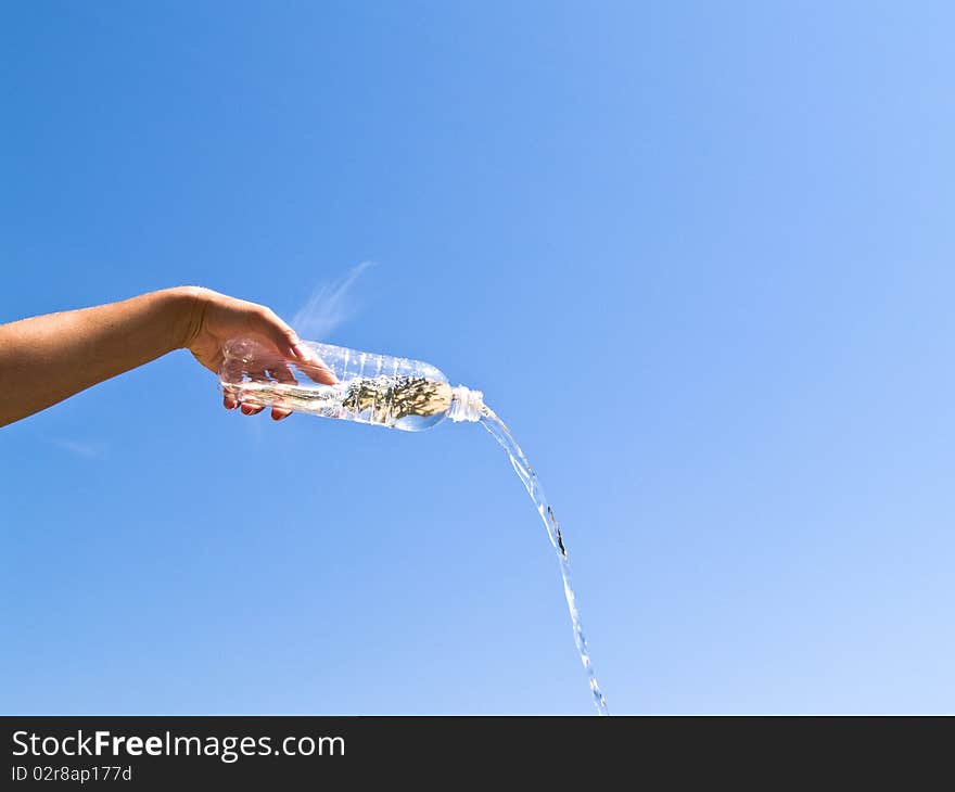 Hand holding bottle of water on the blue sky background