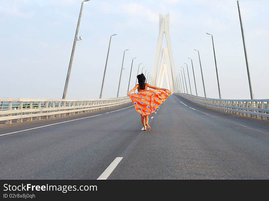 Young adult walking over  bridge with flying red scarf