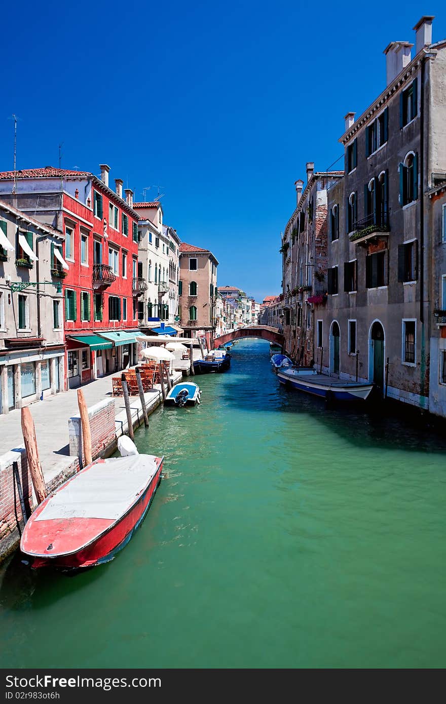 View of beautiful colored venice canal with bridge and houses standing in water