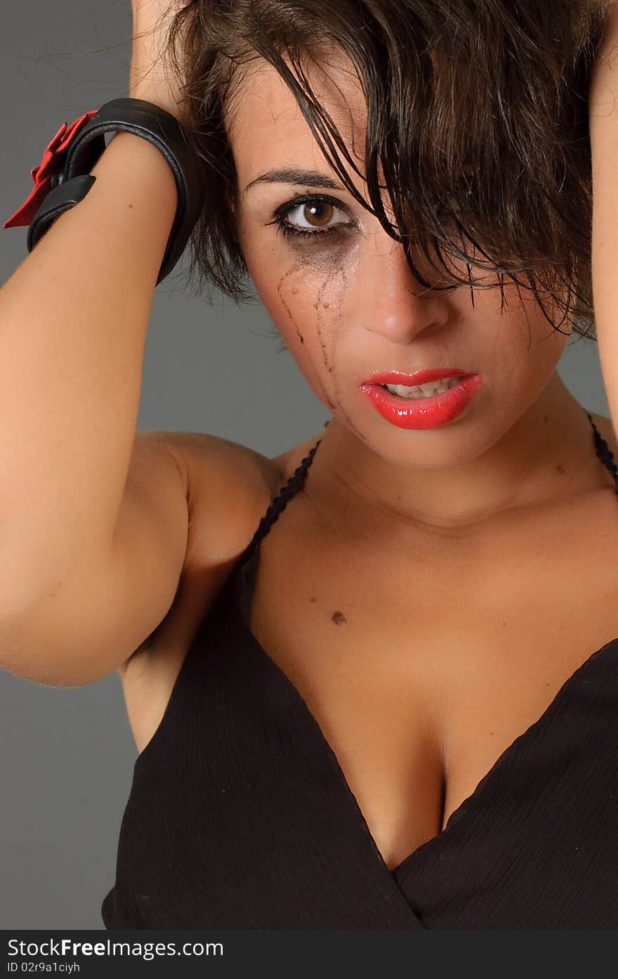 Tearful woman in black dress posing in studio