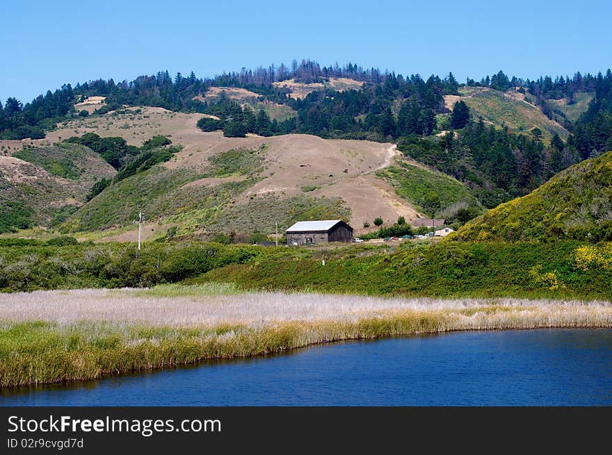 An old barn in the distance sitting beside a California beach.