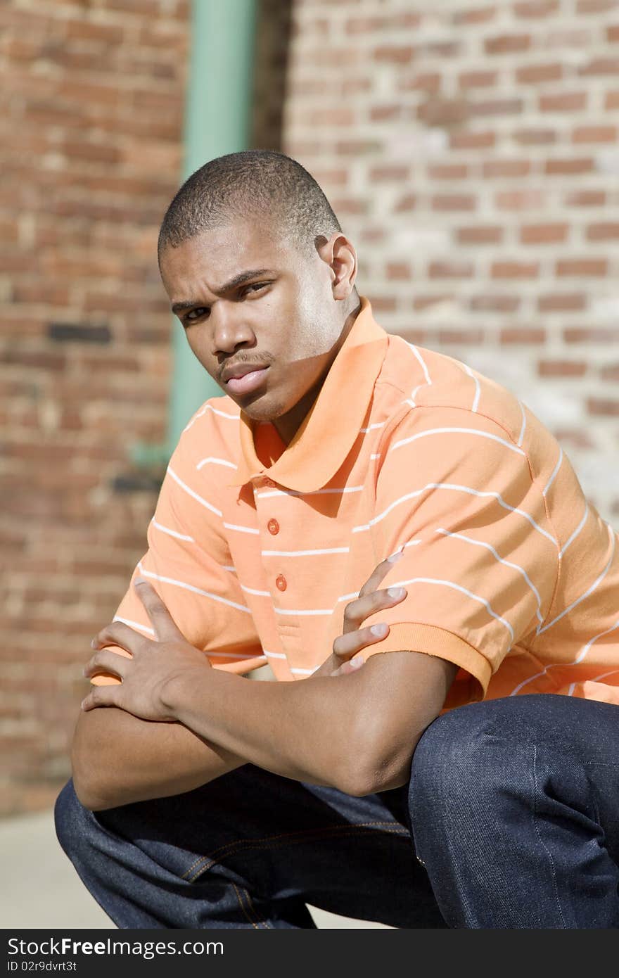 Handsome African American male model posed in front of a brick background. Handsome African American male model posed in front of a brick background.