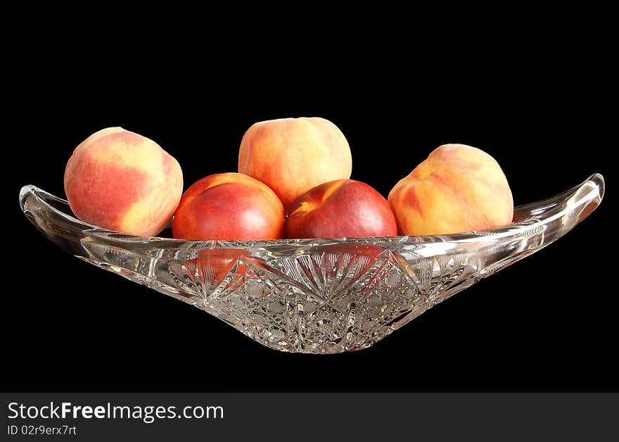 Big, ripe nectarines and peaches in a crystal vase for fruits