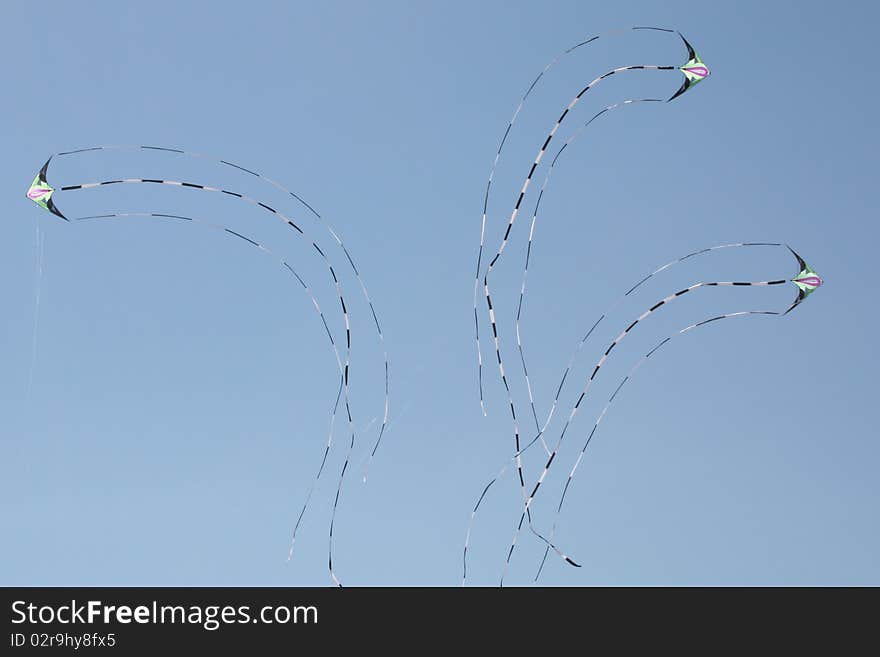 Three identical kites flying and turning in the blue sky