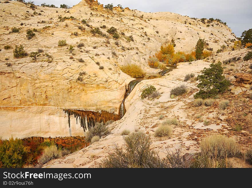 White slickrock mountaintop with waterfall cascading through the trail. White slickrock mountaintop with waterfall cascading through the trail