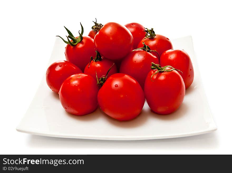 Fresh tomatoes on white plate. Isolated on white background